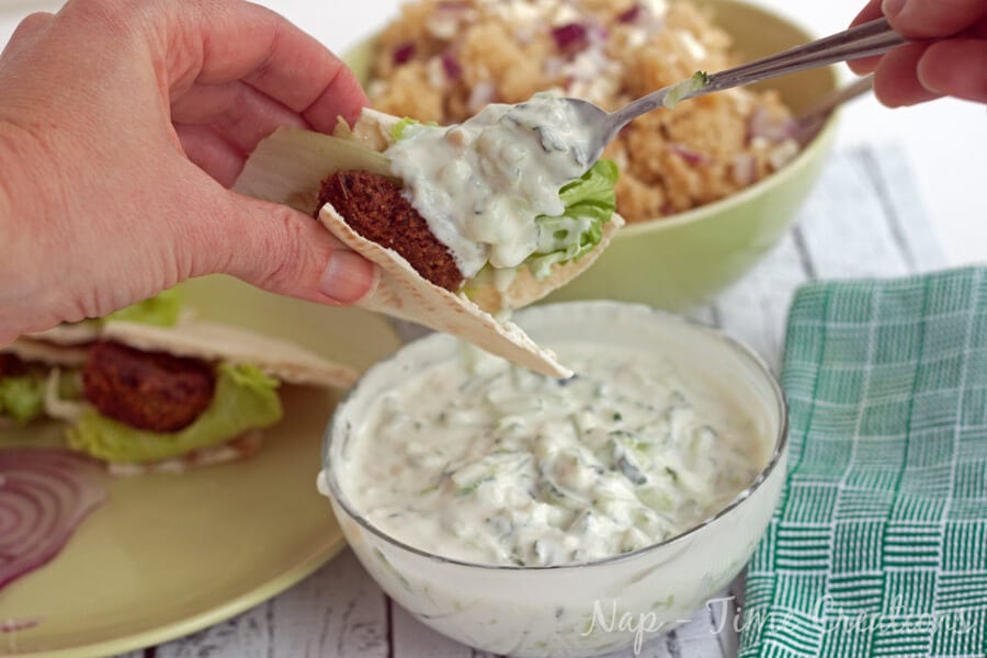 Dip in a bowl and being put inside pita bread with a spoon.